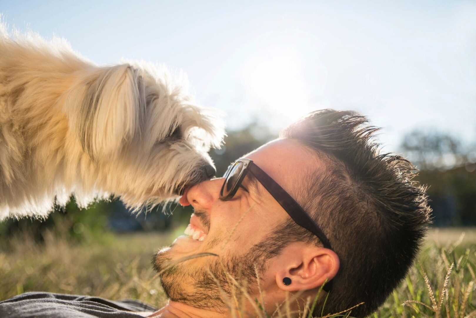 A man and his dog are laying in the grass.