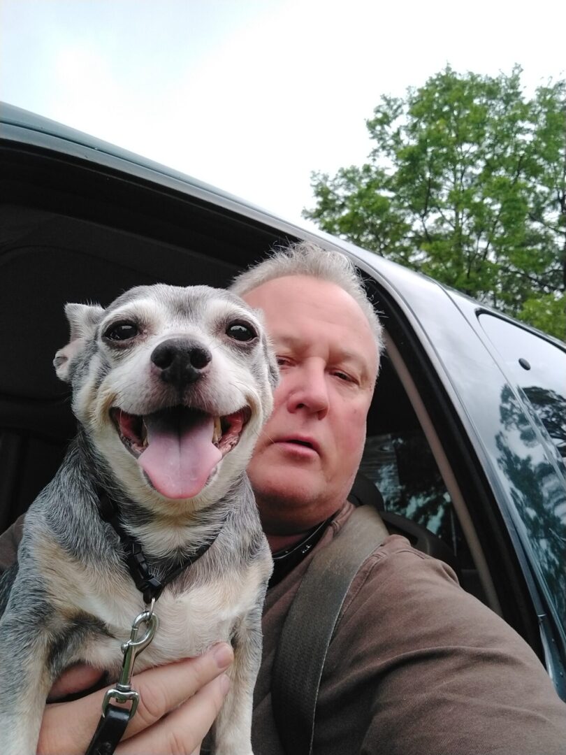 A man and his dog are in the back of their car.